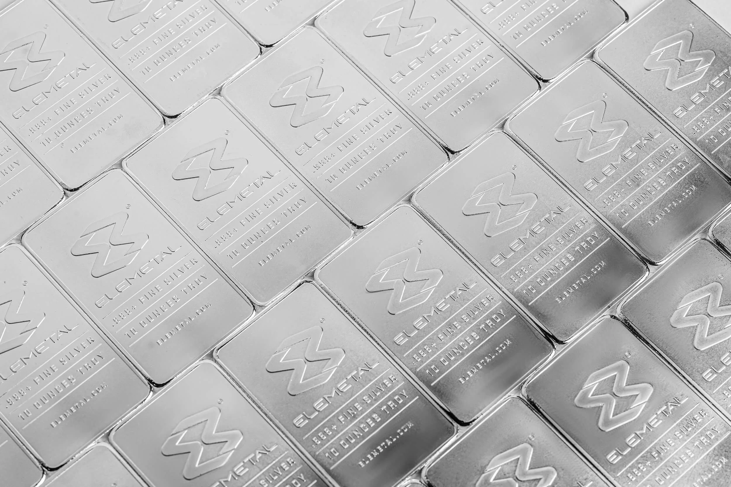 Stacked Elemetal pure fine silver bars with embossed logos and ten ounce troy markings arranged in rows