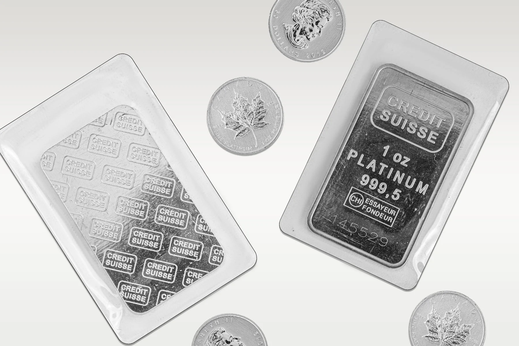 Credit Suisse platinum bars and Canadian platinum coins displayed on white background