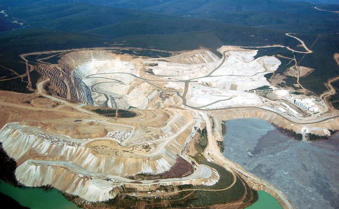 Aerial view of large open-pit gold mine with terraced excavation and access roads